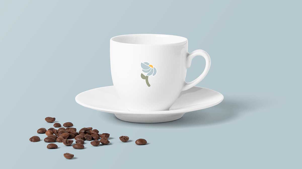Ceramic coffee cup that is white with a blue flower logo mark in the middle