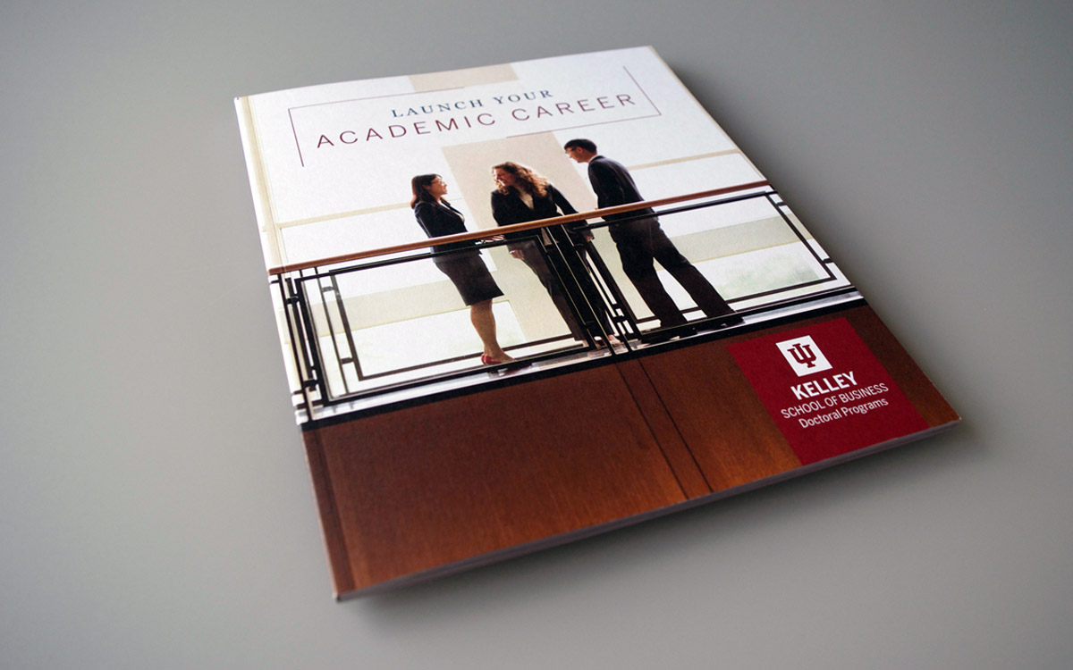 Doctoral Viewbook cover showing three PhD students standing inside in business attire talking