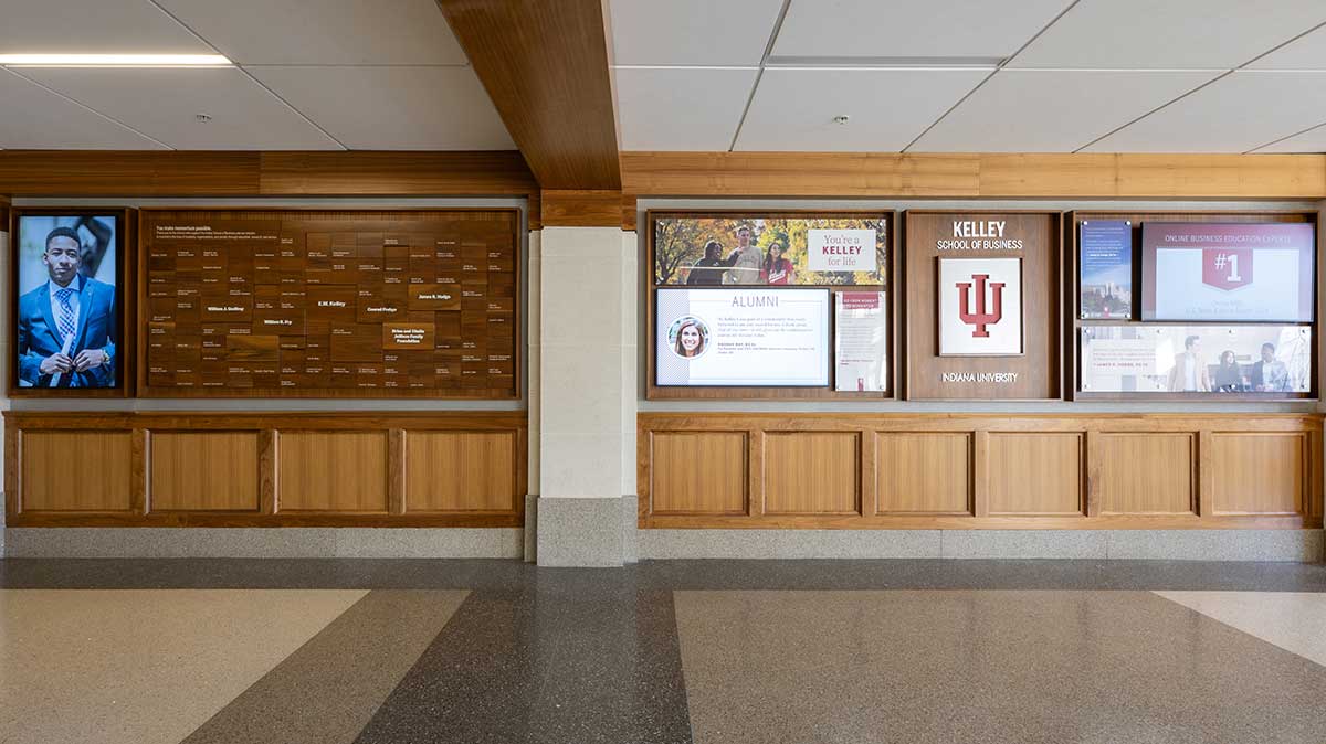 University donor wall featuring a sleek, modern design with engraved donor names, images of campus and student success stories, and rotating digital screens displaying donor recognition and impact highlights."