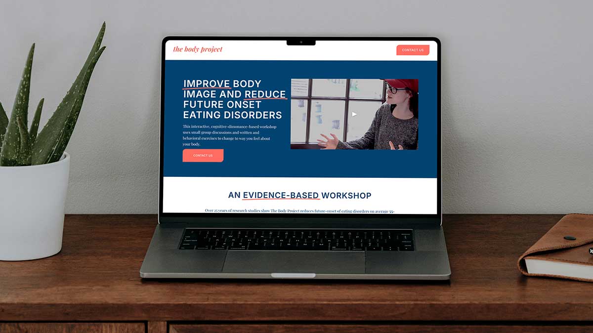 A computer on a credenza with a blue and coral website shown